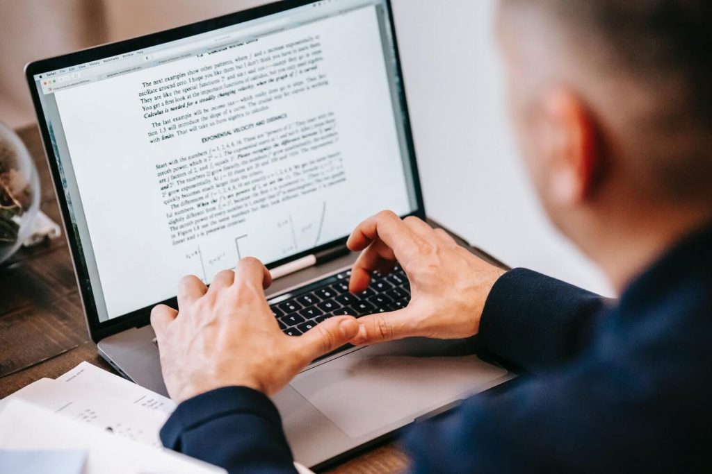 A man writing standard operating procedure (SOPs) on laptop